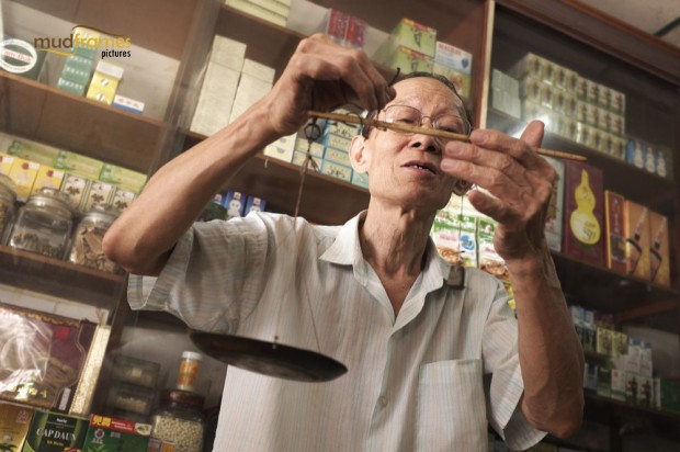 A traditional chinese medicine practitioner using the traditional chinese weighing scale at Kok Ann medical store at Kuching, Malaysia